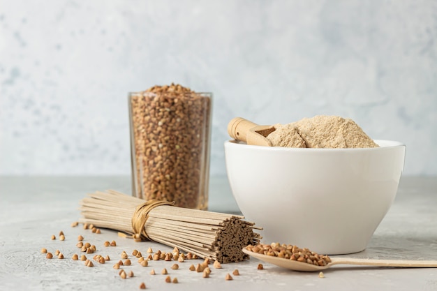 Schüssel mit glutenfreiem Buchweizenmehl, Buchweizenkörnern in einem Glas und Sobanudeln