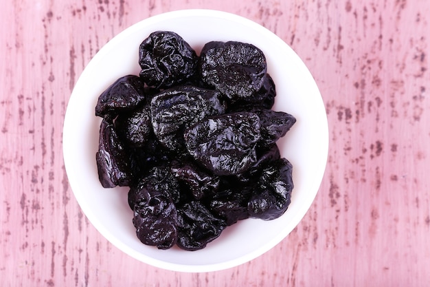 Schüssel mit Haufen Pflaumen auf Farbe Holz