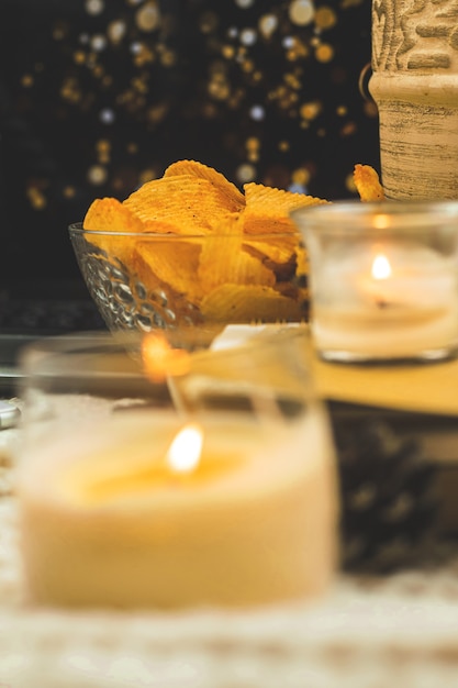 Schüssel mit Kartoffelchips, ungesundes Essen für abendliches Fernsehen, gemütlicher Winter und warmer Herbsthintergrund. Foto in hoher Qualität