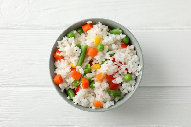 Schüssel mit köstlichem Reis mit Gemüse auf Holzoberfläche