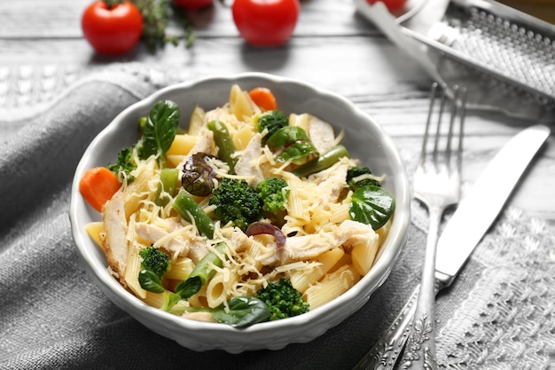 Schüssel mit leckerem Hühnchen und Nudeln auf dem Tisch