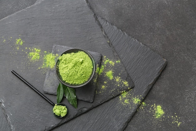 Schüssel mit Matcha-Pulver-Tee und Schaufel auf schwarzem Hintergrund