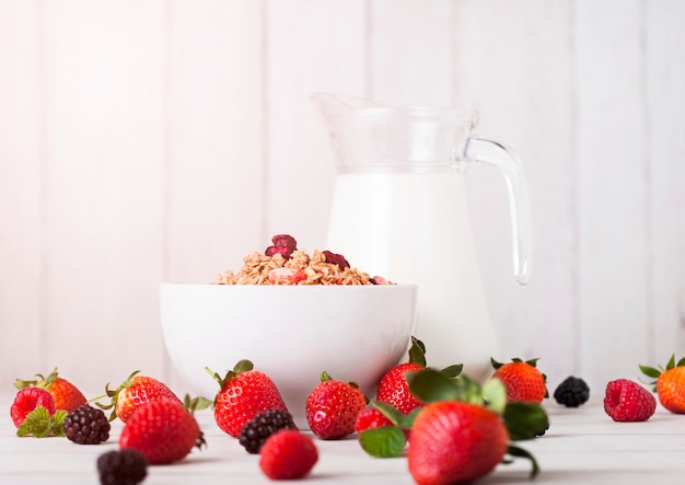 Schüssel mit Müsli und frischen Beeren und Glas Milch. Gesundes Sommerfrühstück