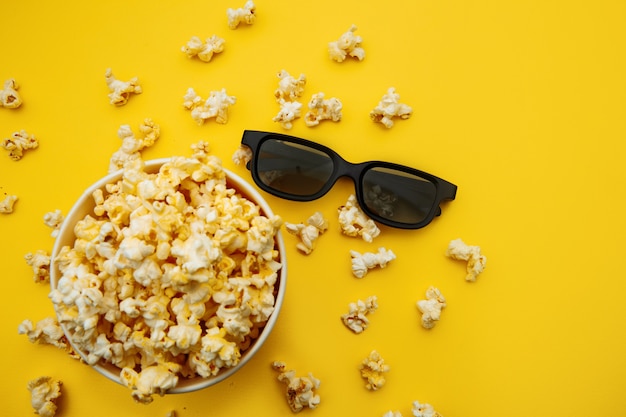 Schüssel mit Popcorn und 3D-Gläsern auf einem gelben