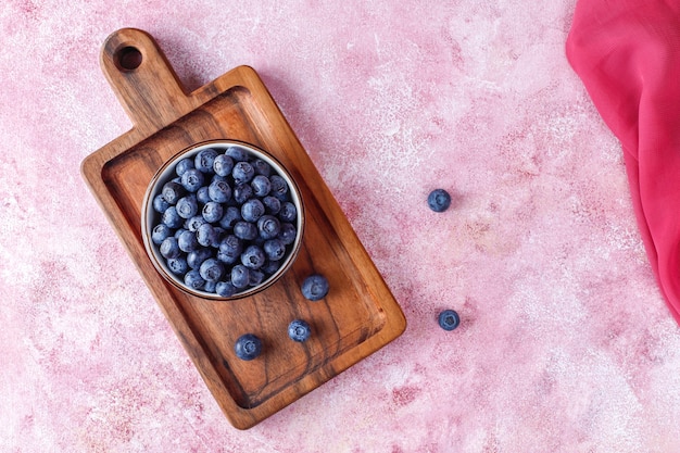 Schüssel mit reifen frischen Blaubeeren auf Holzbrett