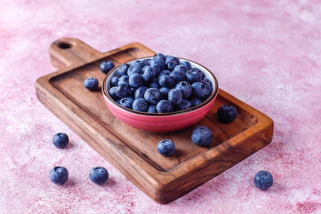 Schüssel mit reifen frischen Blaubeeren auf Holzbrett