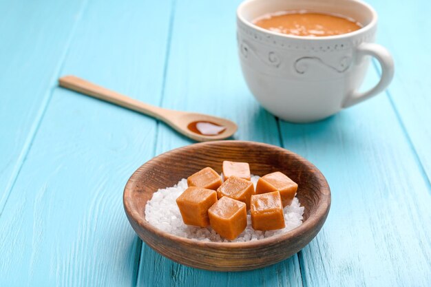 Schüssel mit Salz- und Karamellbonbons auf farbigem Holzhintergrund