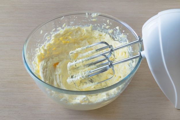 Schüssel mit Schlagsahne und elektrischem Handmixer