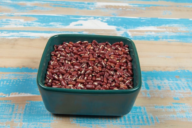 Schüssel mit schwarzen Bohnen auf blauem rustikalem Holztisch