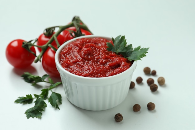 Schüssel mit Tomatenmark, Tomaten, Pfeffer und Petersilie auf weißem Hintergrund