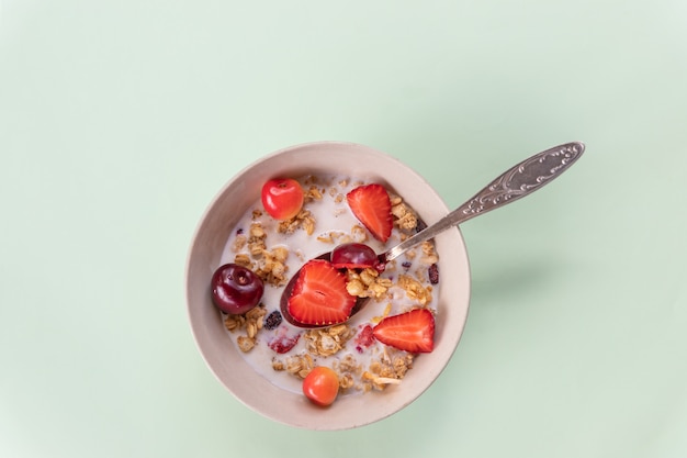 Schüssel Müsli und Joghurt mit frischen Kirschen, Erdbeeren. Schalen mit Haferflocken, Beeren und frischer Milch