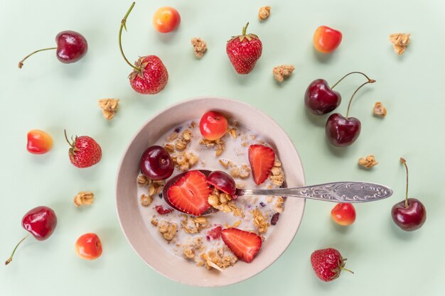 Schüssel Müsli und Joghurt mit frischen Kirschen, Erdbeeren. Schalen mit Haferflocken, Beeren und frischer Milch