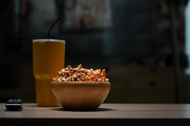 Schüssel Popcorn und Fernbedienung auf Holztisch im Wohnzimmer