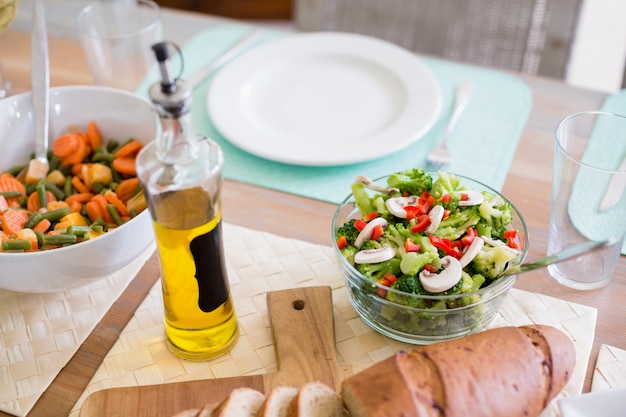 Schüssel Salat und Olivenöl auf Esstisch