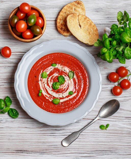 Schüssel Tomatensuppe mit einem Basilikum auf hölzernem Hintergrund