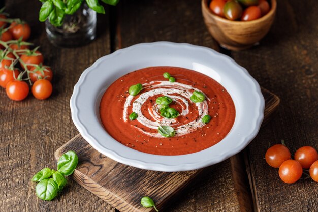 Schüssel Tomatensuppe mit einem Basilikum auf hölzernem Hintergrund