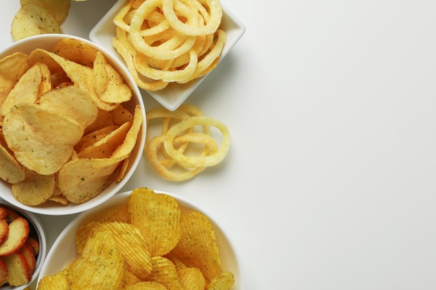 Schüsseln mit verschiedenen Snacks auf Weiß