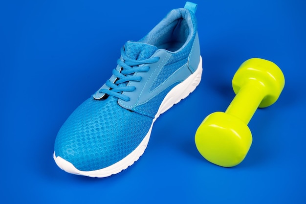 Schuhe für das Training mit Hantel auf blauem Hintergrund, Sportzubehör.