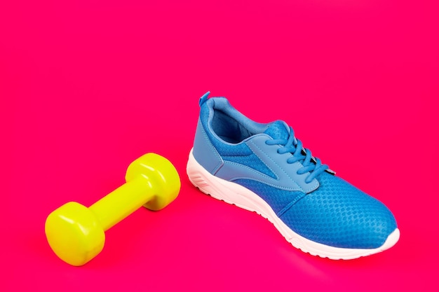 Schuhe für das Training mit Hantel auf rosa Hintergrund, Sport.