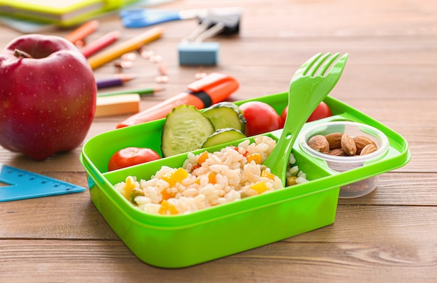 Schul-Lunchbox mit leckerem Essen auf hölzernem Hintergrund