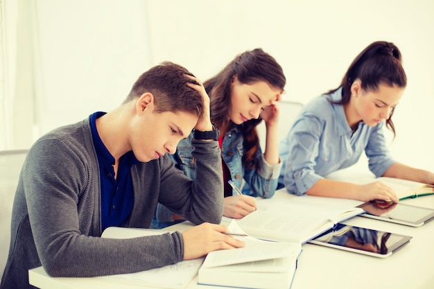 schul- und bildungskonzept - gruppe müder schüler mit notizbüchern in der schule