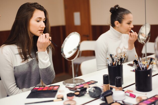 Schule des Schminkens. Visagistin, die professionelles Make-up der jungen Frau macht.