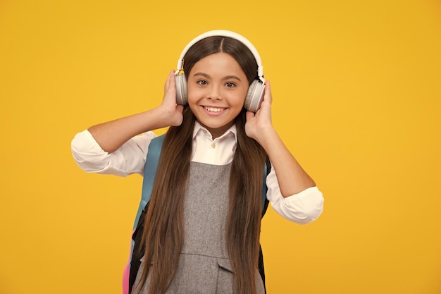 Schule Teenager Kind Mädchen in Kopfhörern mit Schulrucksack Teenager Student isoliert Hintergrund Musik lernen Glückliches Mädchen Gesicht positive und lächelnde Emotionen