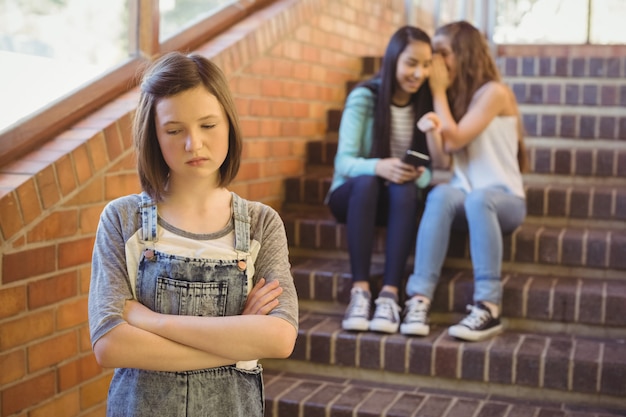 Schulfreunde, die ein trauriges Mädchen im Schulkorridor schikanieren