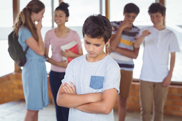 Schulfreunde schikanieren einen traurigen Jungen im Korridor