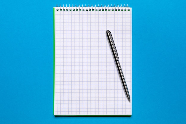 Schulheft auf einer blauen Oberfläche, gewundener Notizblock auf einer Tabelle