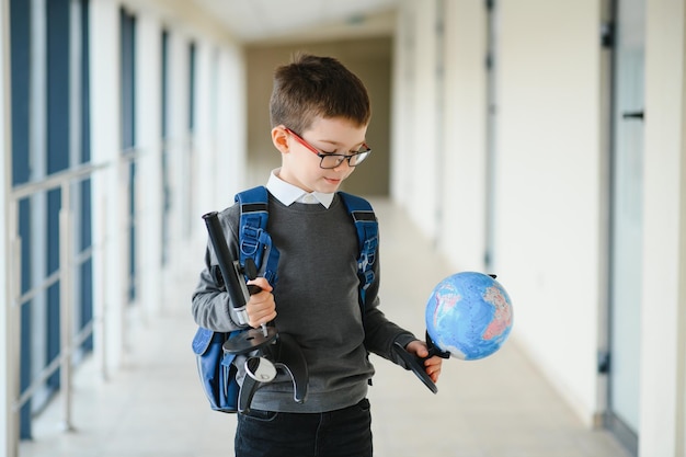 Schuljunge mit Schultasche und Büchern in der Schule Bildungskonzept Zurück zur Schule Schulkind, das zur Klasse geht Stilvoller Junge mit Rucksack Junge bereit zu studieren