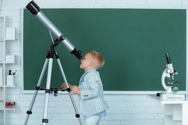 Schuljunge mit Teleskop lernt Astronomieunterricht in der Schule