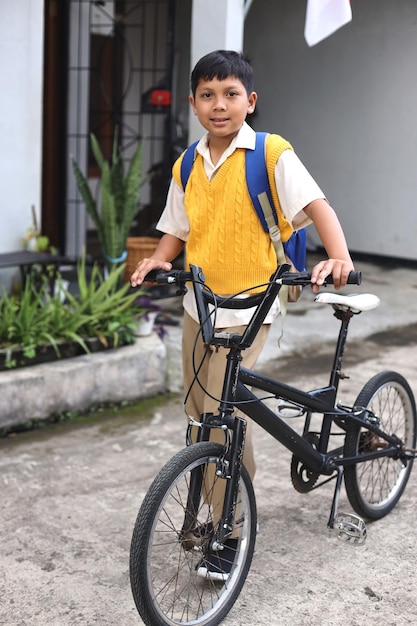 Schuljunge trägt Uniform und Rucksack und ist bereit, mit dem Fahrrad zur Schule zu fahren. Fahrrad zur Schule