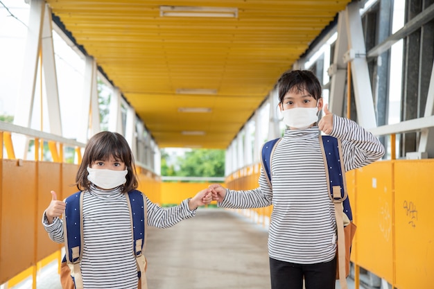 Schulkind, das während des Ausbruchs des Coronavirus eine Gesichtsmaske trägt Kleines Mädchen, das wieder zur Schule geht