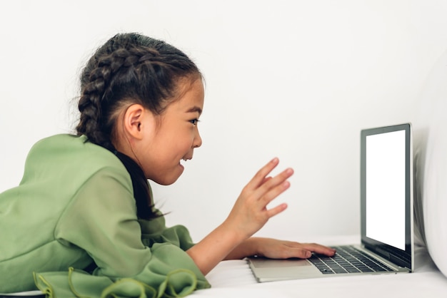 Schulkind kleines Mädchen lernen und betrachten Laptop-Computer machen Hausaufgaben studieren Wissen mit Online-Bildung E-Learning-System.