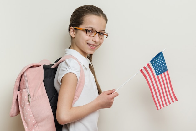 Schulkind mit Rucksack hält die US-Flagge