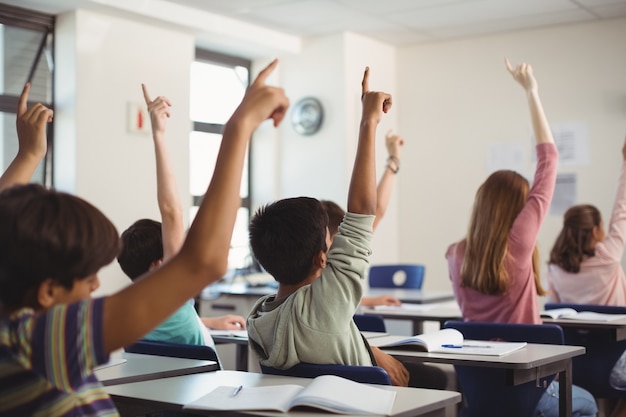 Schulkinder, die Hand im Klassenzimmer erheben