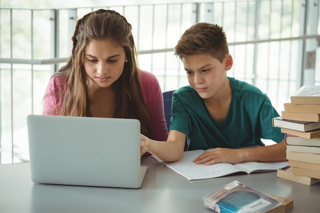 Schulkinder, die Laptop in Bibliothek verwenden