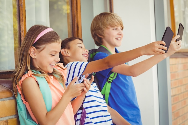 Schulkinder, die selfie nehmen und Handy im Korridor verwenden