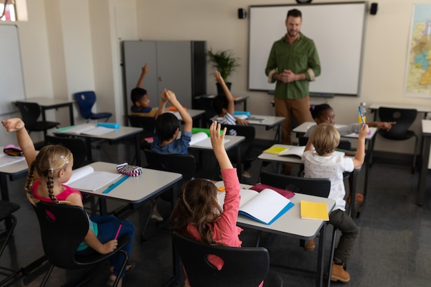 Schulkinder erheben die Hand im Klassenzimmer der Grundschule