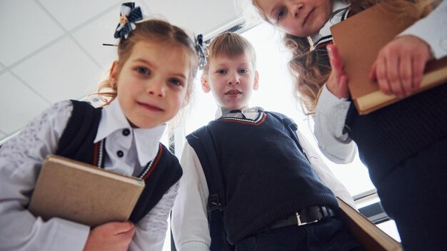 Schulkinder in Uniform posieren gemeinsam für eine Kamera im Korridor Konzeption der Bildung