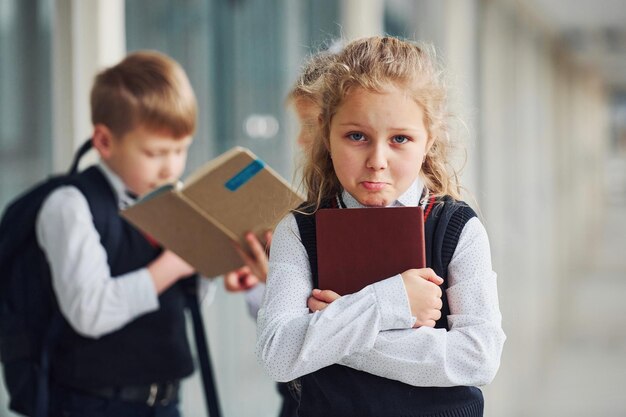 Schulkinder in Uniform zusammen mit Büchern im Korridor Konzeption der Bildung