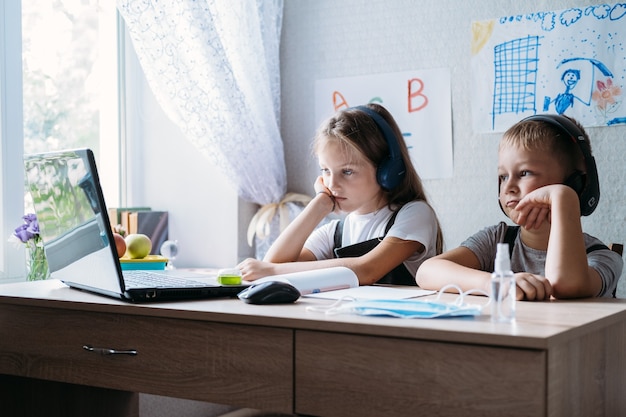 Schulkinder Jungen und Mädchen mit Laptop für Online-Lernen während des Homeschooling zu Hause Homeschooling