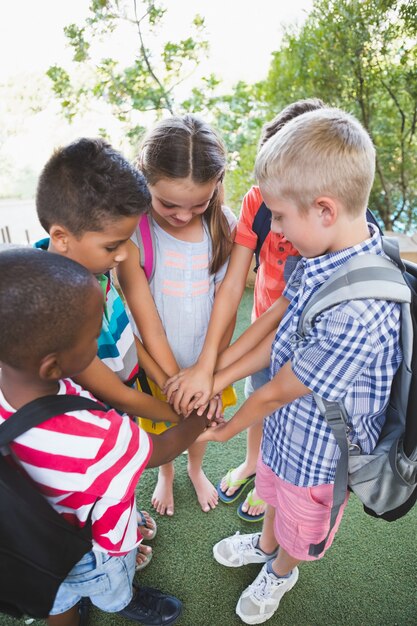 Schulkinder legen ihre Hände auf dem Campus zusammen