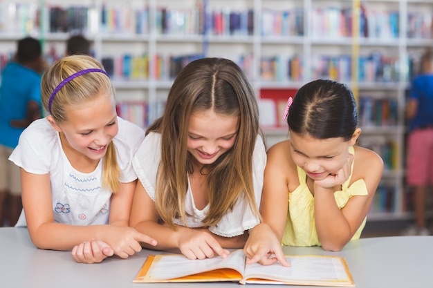Schulkinder lesen zusammen Buch in der Bibliothek