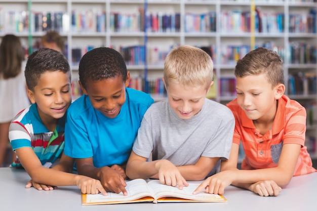 Schulkinder lesen zusammen Buch in der Bibliothek