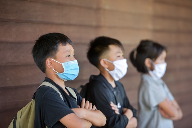 Schulkinder mit Schutzmaske gegen Grippeviren im Unterricht im Klassenzimmer