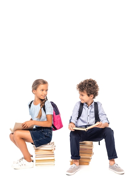 Schulkinder sitzen auf Büchern und sehen sich isoliert auf weiß an