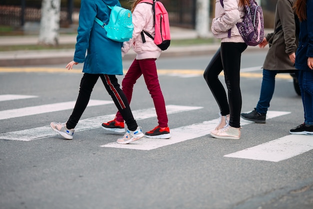 Schulkinder überqueren die Straße in medizinischen Masken. Kinder gehen zur Schule.