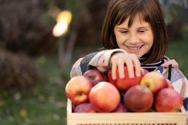 Schulkindermädchen nehmen roten Apfel und essen eine weibliche Apfelhand, die Bio-Früchte auswählt